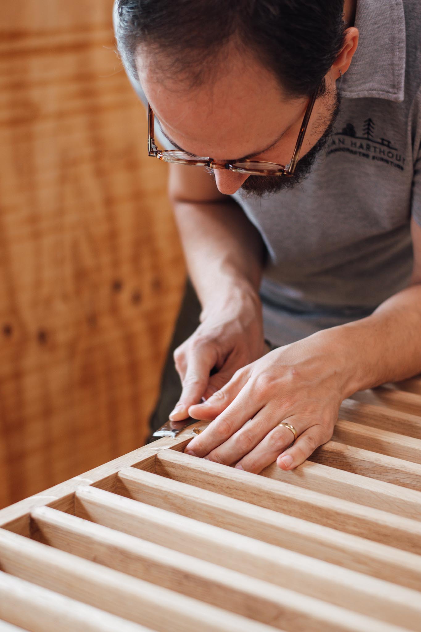 Meubelmaker Twan is met een beitel de houtverbindingen van een op maat gemaakte roomdivider aan het verfijnen in zijn atelier in Eindhoven.