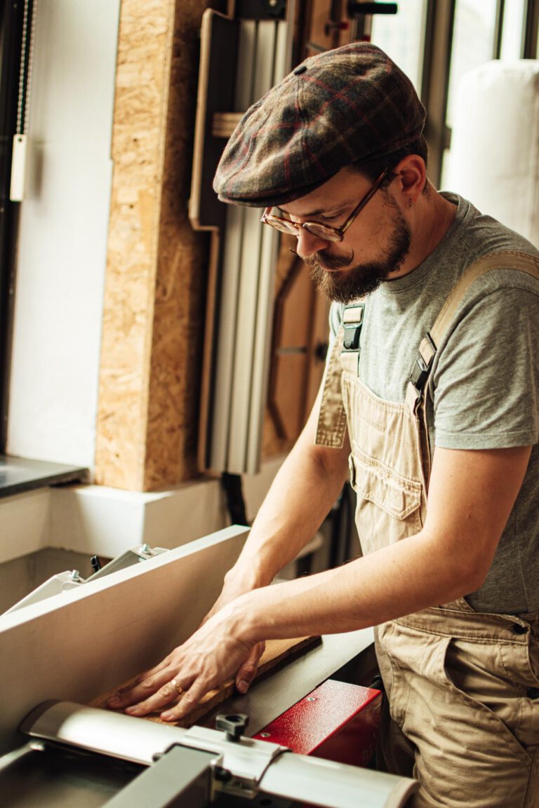 Ambachtelijk meubelmaker Twan is massief eikenhout van landgoed De Wielewaal aan het schaven op de vlakbank in zijn atelier in de Apparatenfabriek op Strijp-S, Eindhoven.